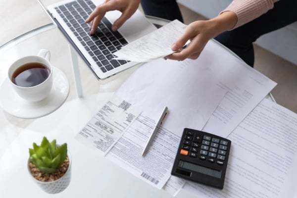 Hands on keyboard with calculator and receipts