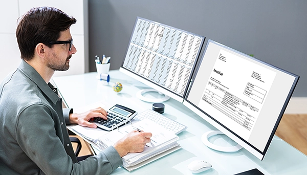 Office worker looking at invoices on desktop computer